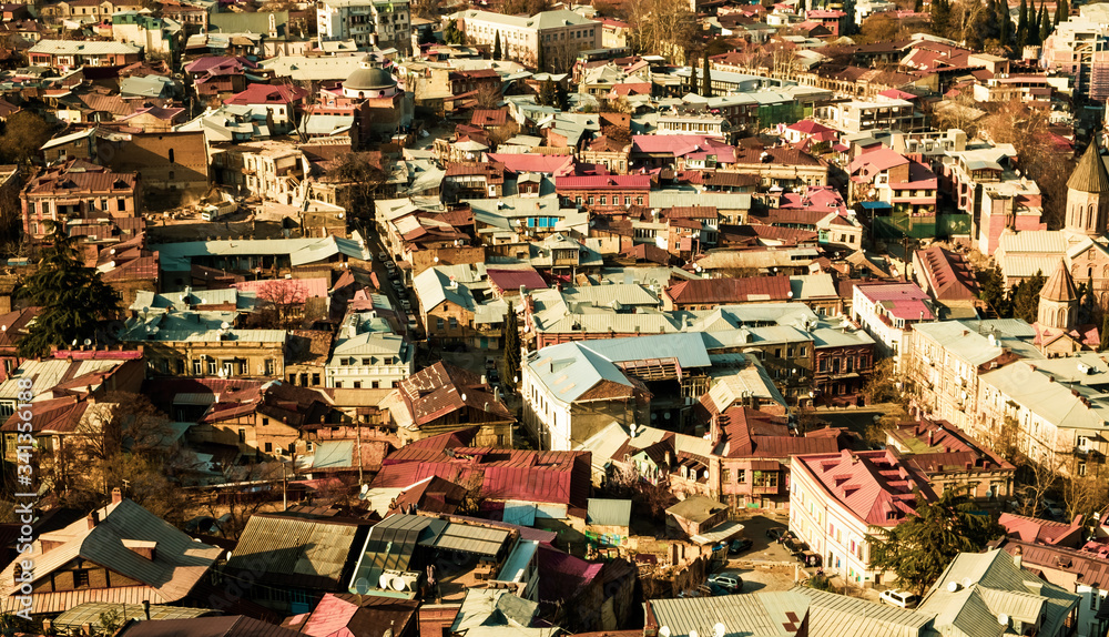 Fototapeta premium Panorama of the city of Tbilisi from a high point. Tiled roofs of old houses. View of the old city.