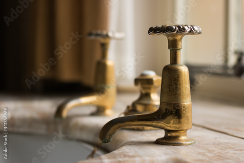 Close-up: a Vintage Copper Water Tap for Washing Hands in a Bathroom of House. Old Fashioned, Without Mixer. Traditional Retro Symbol of English House Style. 