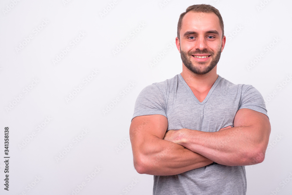 Fototapeta premium Portrait of happy muscular bearded man smiling with arms crossed