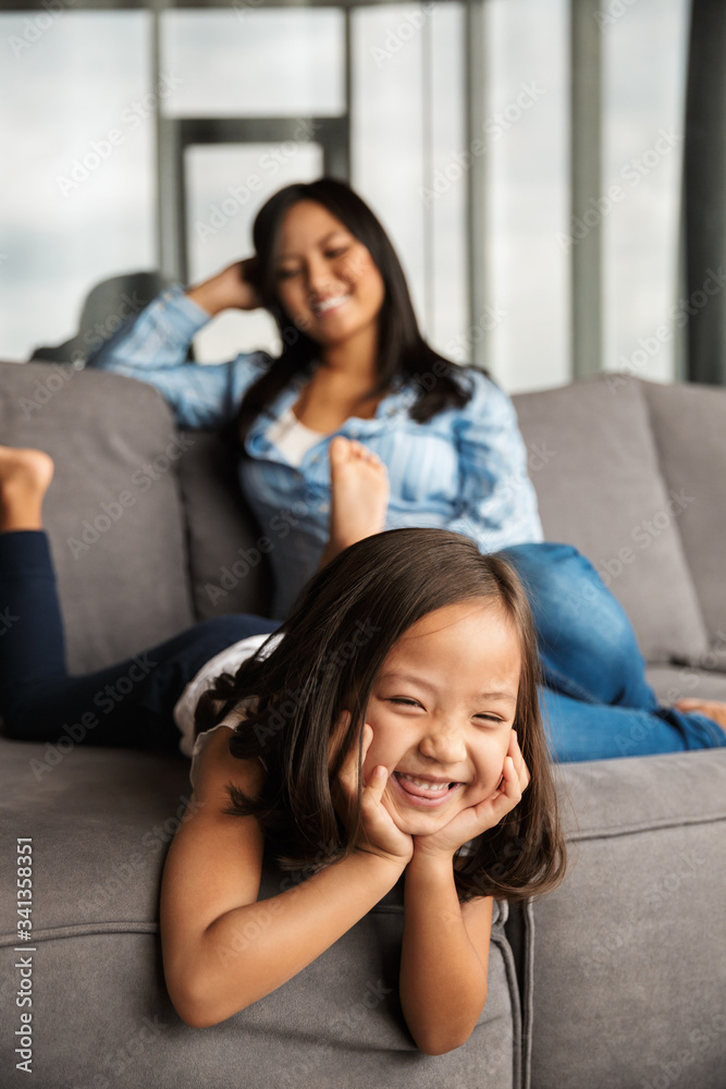 Photo of woman with her daughter laughing while resting on couch Photo of woman with her daughter laughing while resting on couch
