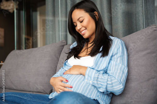 Photo of happy pregnant woman smiling and touching her belly