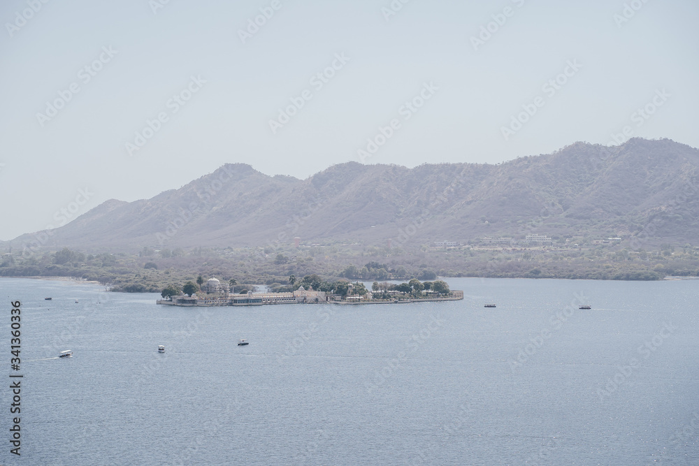 View of Lake Pichola and floating palace, mountains in the background in Udaipur, India