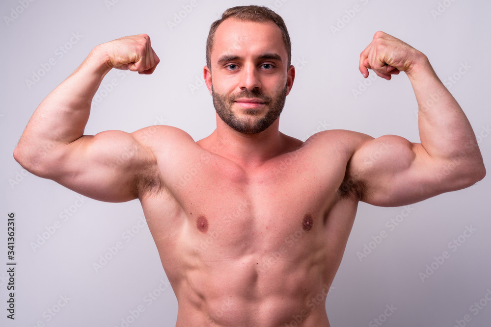 Portrait of muscular bearded man flexing both arms shirtless Portrait of muscular bearded man flexing both arms shirtless