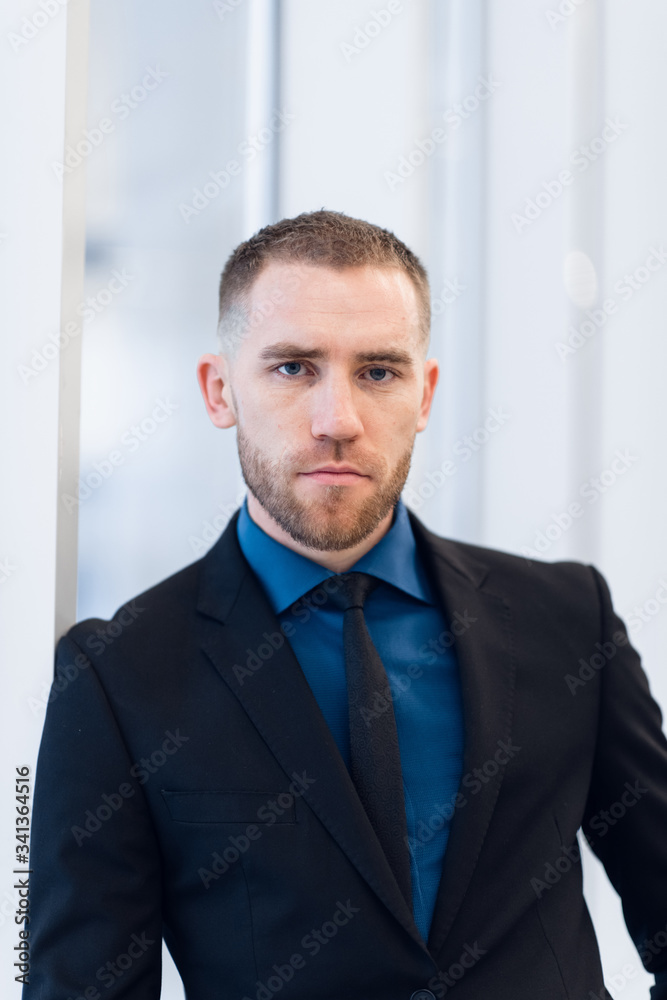 Middle-aged man standing with folded arms leaning against a windowsill turning to look at the camera with a pensive expression Middle-aged man standing with folded arms leaning against a windowsill turning to look at the camera with a pensive expression