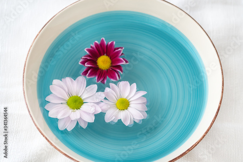 Flower decoration with white and purple daisies, floating in a vintage bowl