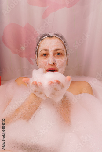 Young woman with a mask on her face is lying in the bathroom.