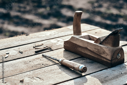 wooden background. Jointer plane and chisel lies on the village table along with sawdust. Wood thread tool. solar lighting