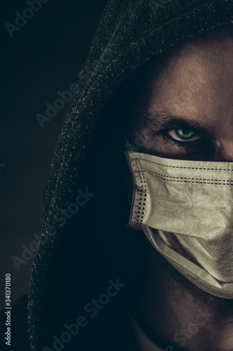 Dark photo of Young handsome man wearing medical protactive face mask in night street photo