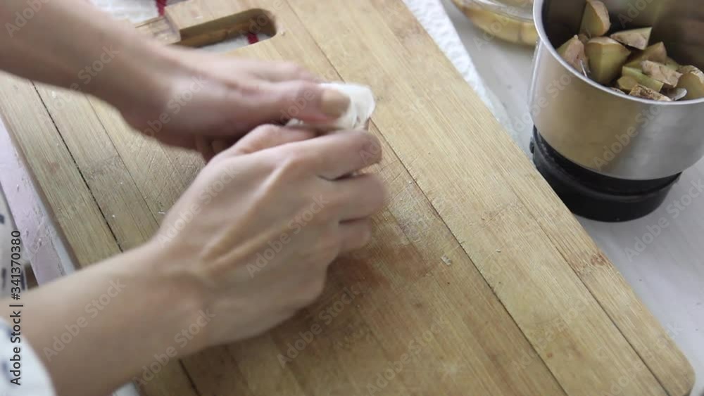 Woman's hand breaking open a garlic bulb on a wooden cutting board