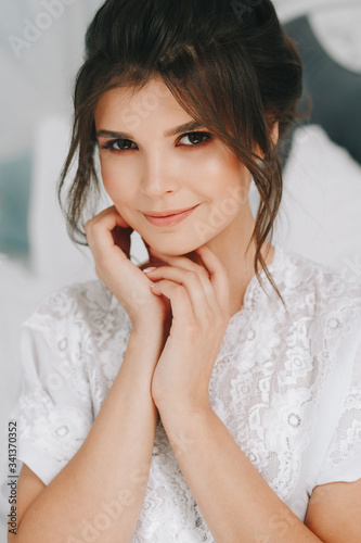 large boudoir portrait of a young girl in a bathrobe in a four-poster bed, morning gatherings of the bride, young brunette, tender photo, wedding portrait, close-up face, tender hands, sensual smile