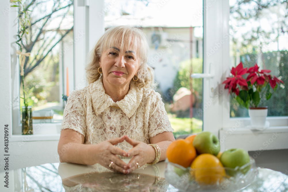Portrait of beautiful senior woman sitting at table at home