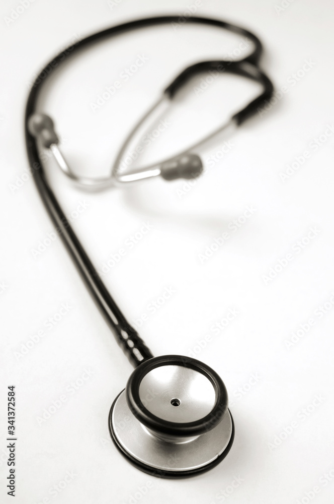 A single black stethoscope over a white tabletop surface. A single black stethoscope over a white tabletop surface.