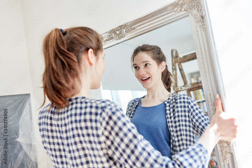 Woman setting up apartment hangs mirror Stock Photo Adobe Stock