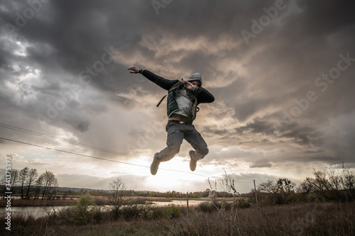 The guy makes a dab during the jump on a beautiful sunset background in field. Concept of modern culture.