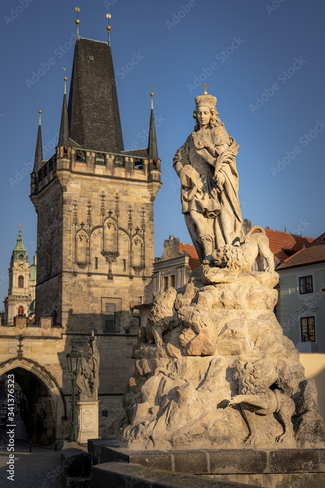 Famous Charles Bridge in Prague. Close u view of the baroque statue of St. Vitus place on the bridge and Lesser Town tower in background