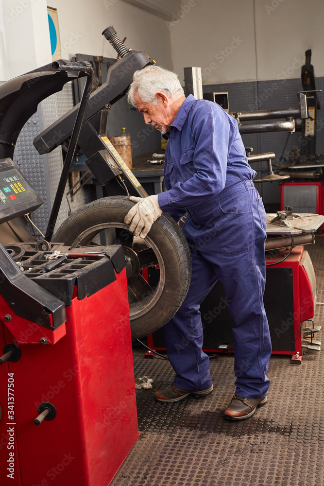 Erfahrener Mechaniker in der KFZ Werkstatt mit Reifen Erfahrener Mechaniker in der KFZ Werkstatt mit Reifen
