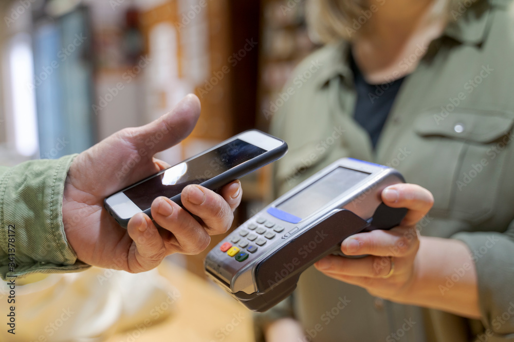 Customer paying contactless with smartphone in a shop Customer paying contactless with smartphone in a shop