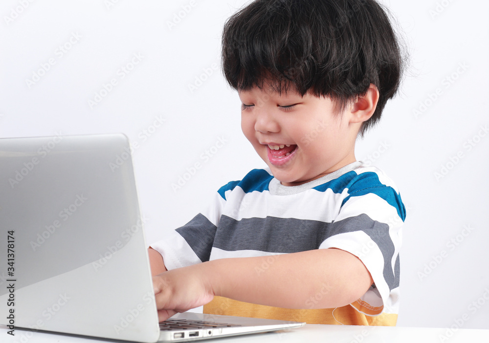 Smart Asian boy using a laptop computer on a desk at home. Online education concept.