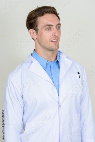 Portrait of happy young handsome man doctor thinking