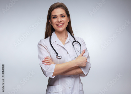 Woman doctor in white uniform standing with crossed arms.