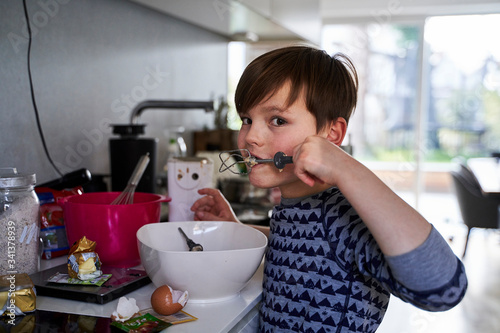 Portrait of boy tasting batter in kitchen photo