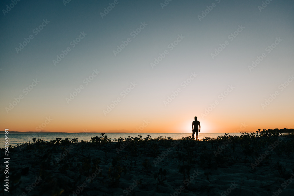 Silhouette of a man enjoying sunset on the beach 