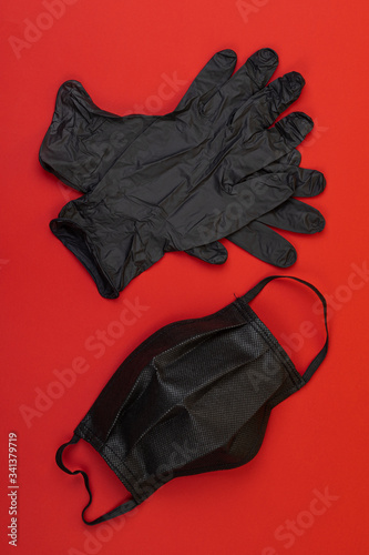 Black mask and gloves on top on a red background © Ners