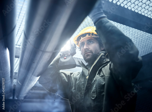 Technician with torch, checking pipework