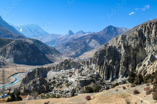 A temple complex in Manang Annapurna Circuit Trek, Nepal. Stupa in front of other buildings. Temple built on a rocky mountain hills. Sacred place for many Buddhist tourists. Dry land. Clear sky.