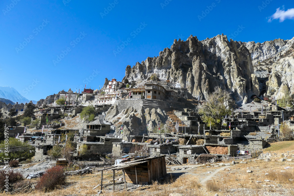 A temple complex in Manang Annapurna Circuit Trek, Nepal. Stupa in front of other buildings. Temple built on a rocky mountain hills. Sacred place for many Buddhist tourists. Dry land. Clear sky.