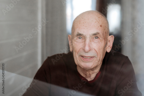 Portrait of smiling old man looking out of window photo