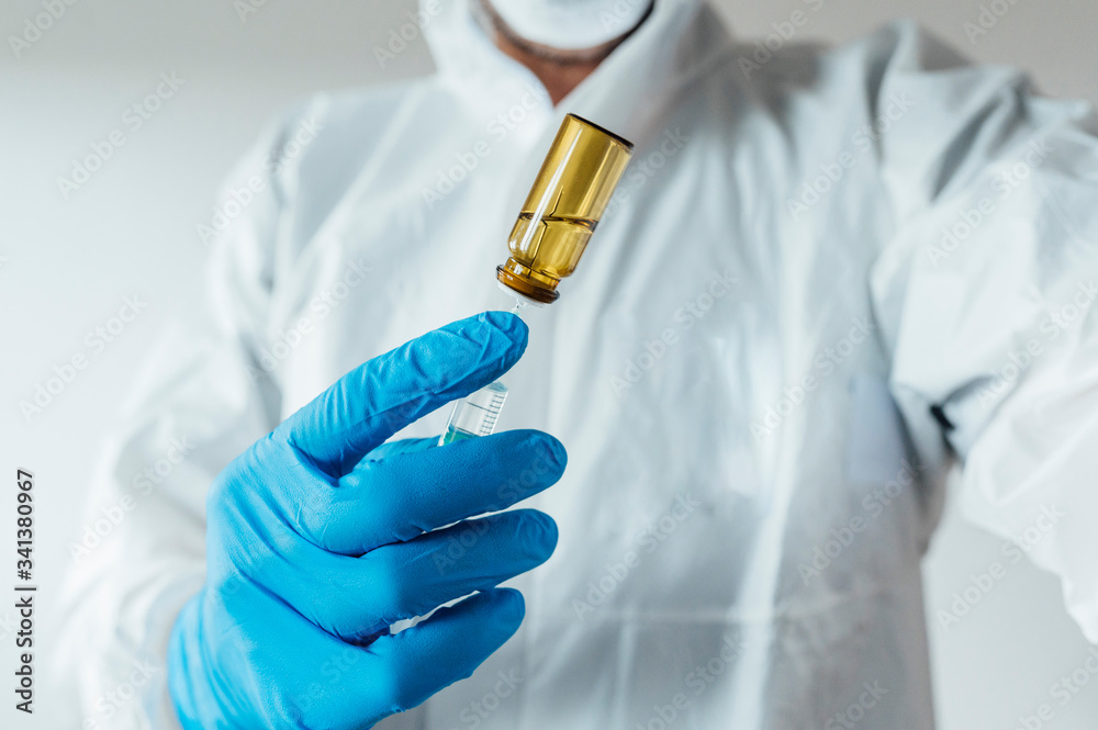 Laboratory technician wearing protective wear, holding vaccine Laboratory technician wearing protective wear, holding vaccine