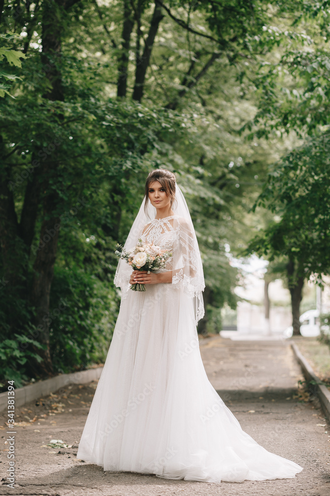 portrait of a bride with flowers in a beautiful full-length wedding dress, young brunette, tender photo wedding portrait