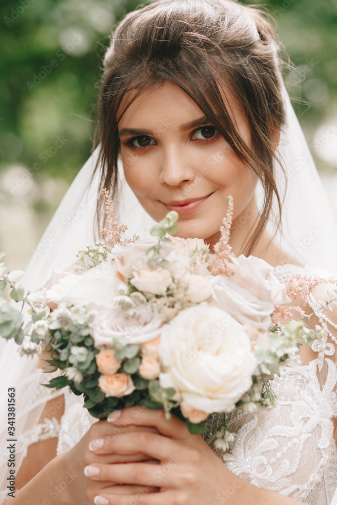 Naklejka premium portrait of a bride with flowers in a beautiful full-length wedding dress, young brunette, tender photo wedding portrait