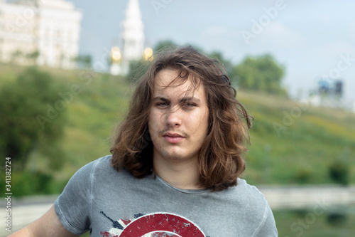 On a summer day, a young man walks in the park and the wind blows his hair