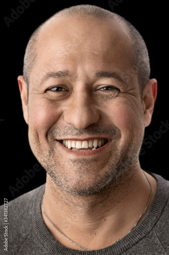 Handsome brutal man with a shaved head smiles broadly and looks at you