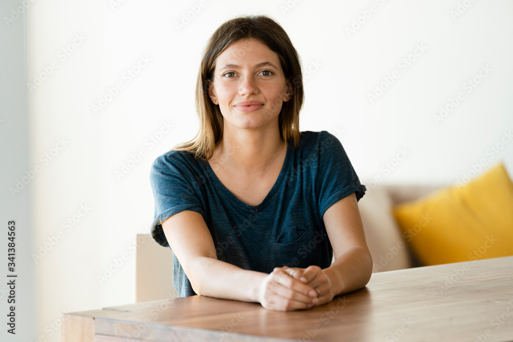 Portrait of confident young woman sitting at table at home Portrait of confident young woman sitting at table at home