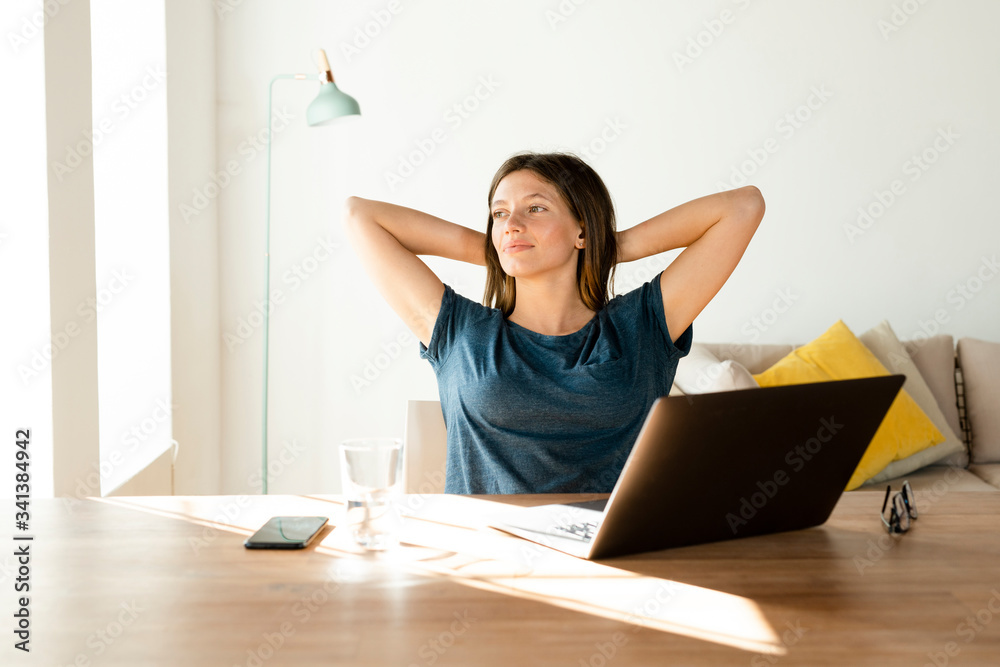 Content young woman at home having a break from working at laptop in home office