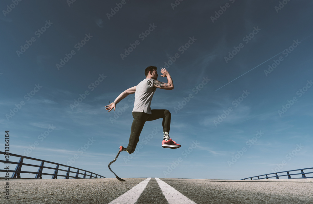 Disabled athlete with leg prosthesis exercising on a road Disabled athlete with leg prosthesis exercising on a road