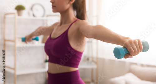 Home fitness. Unrecognizable young girl working out with dumbbells in light room. Panorama