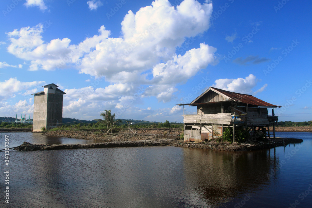 Abandone house on the fish pond. with beautiful clouds and blue sky.