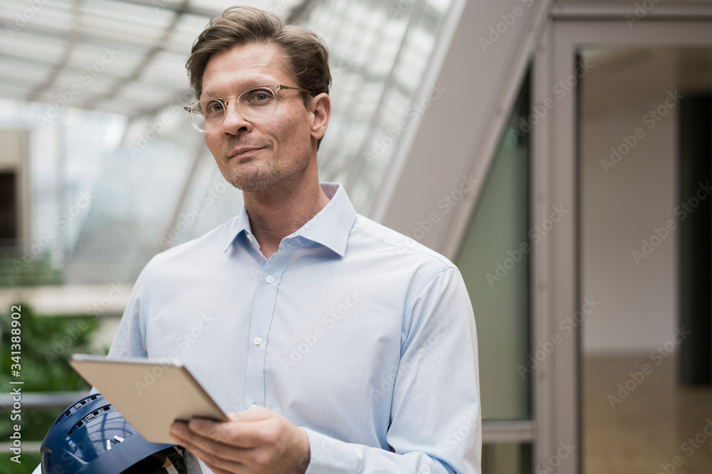 Architcect carrying hard hat, using digital tablet