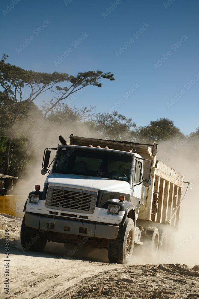 An industrial dump truck transporting dirt in a construction site.
