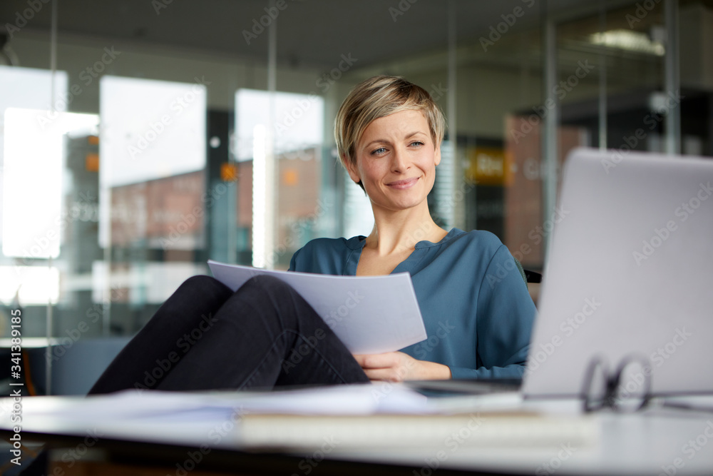 Smiling businesswoman working at desk in office Smiling businesswoman working at desk in office
