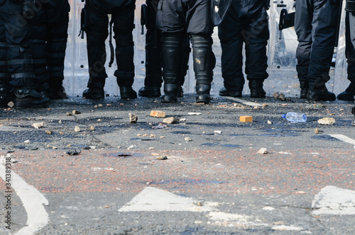 Stones and bricks litter the road as police riot squad move forward after a crowd riots photo