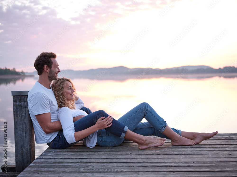 Romantic couple sitting on jetty at the lake Romantic couple sitting on jetty at the lake