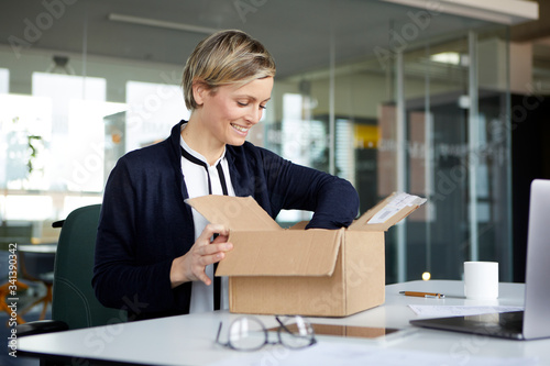Smiling businesswoman unpacking parcel on desk in office
