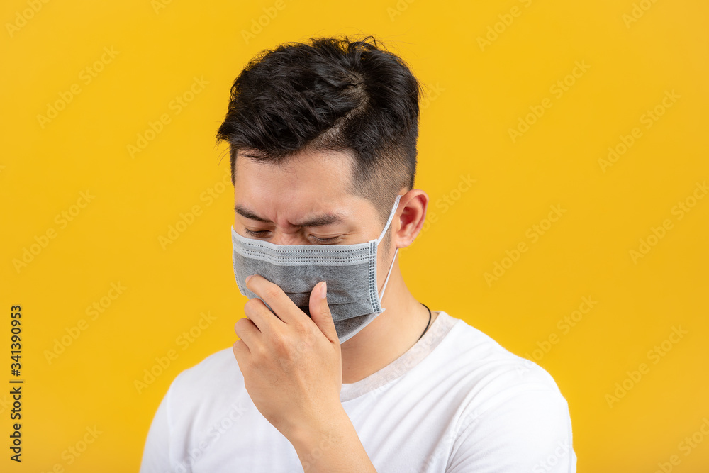 Portrait of a man wearing a medical mask. A man is sneezing from a cold. Spread prevention concept.