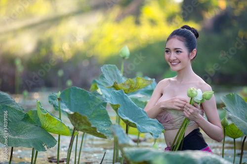 Asian woman harvest lotus flower in the garden,