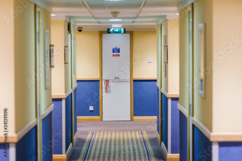 Corridor in a hotel looking down towards a fire escape.